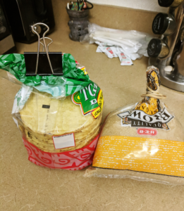A bag of tostadas with a binder clip and a bag of brown sugar with a rubberband.