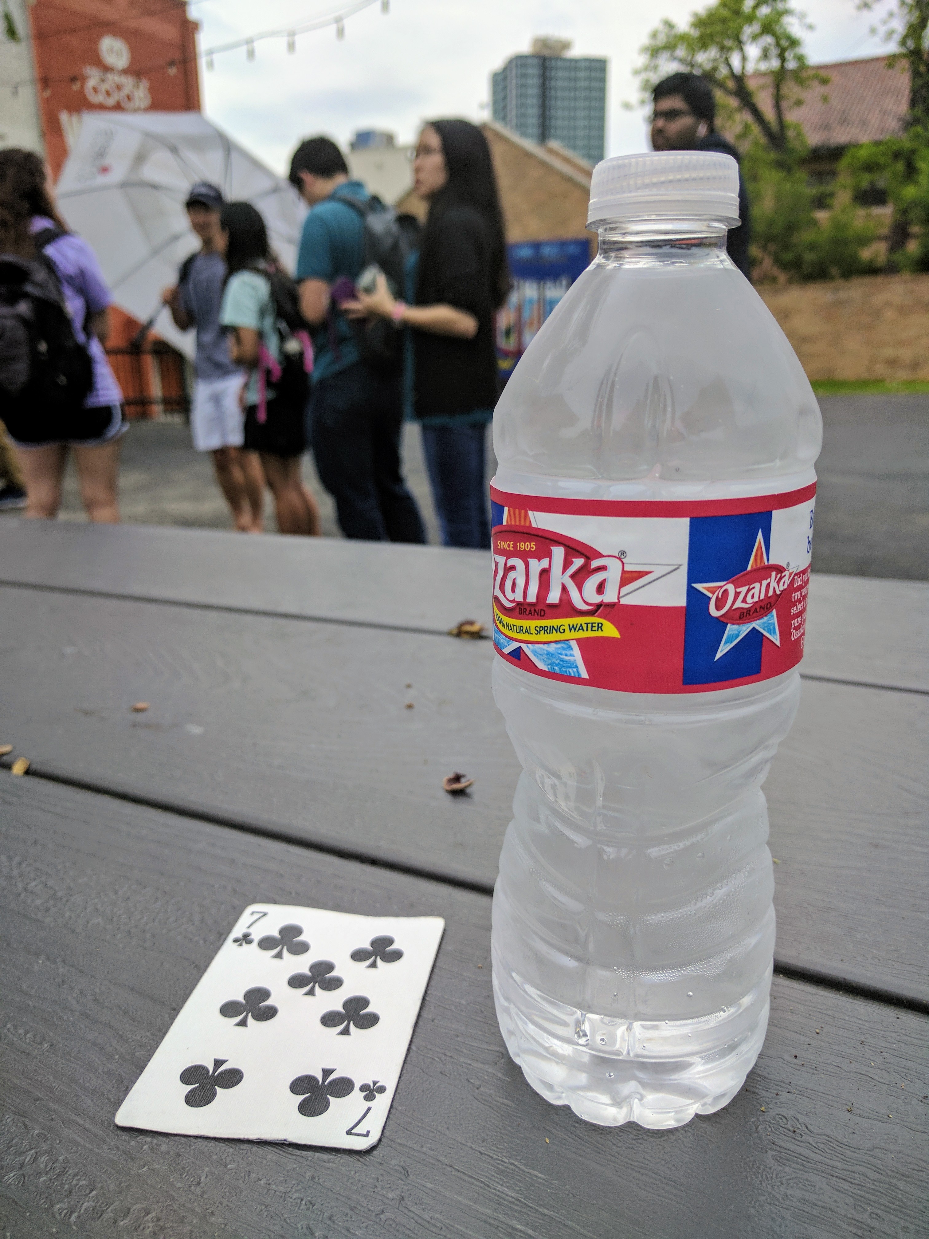 Photo of a playing card next to a bottle of water on a picnic table