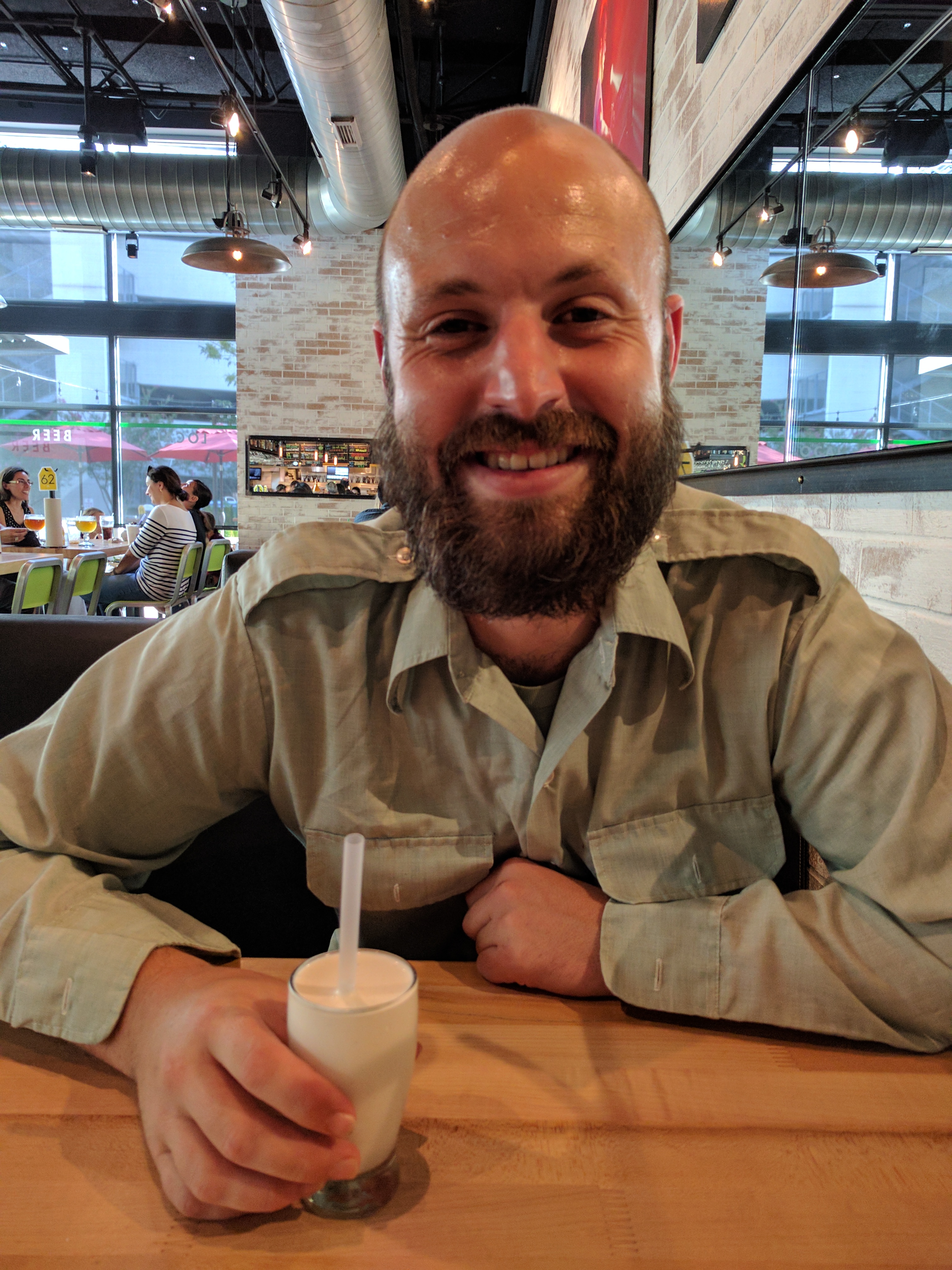 Smiling man holding a tiny milkshake