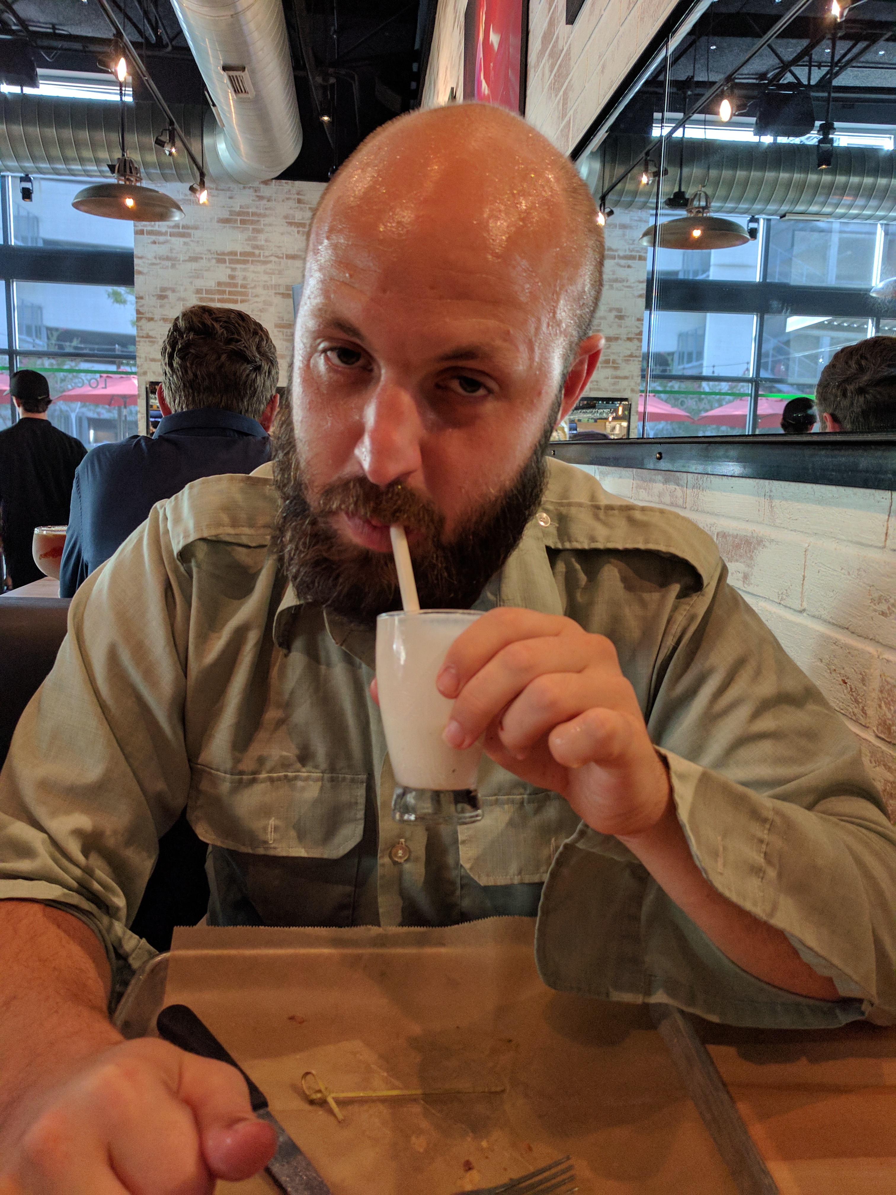 Sweaty man drinking a tiny milkshake