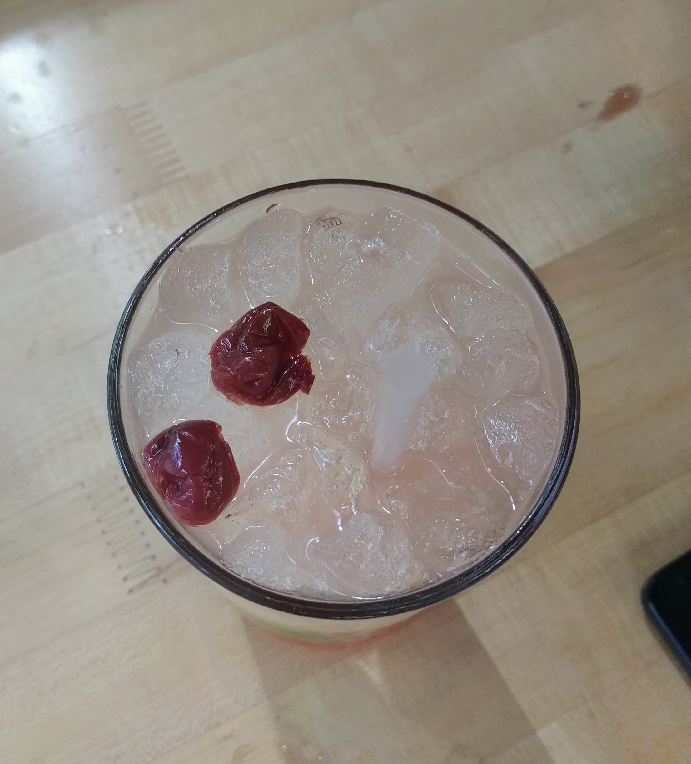 Top down view of a drink with two cherries floating on top
