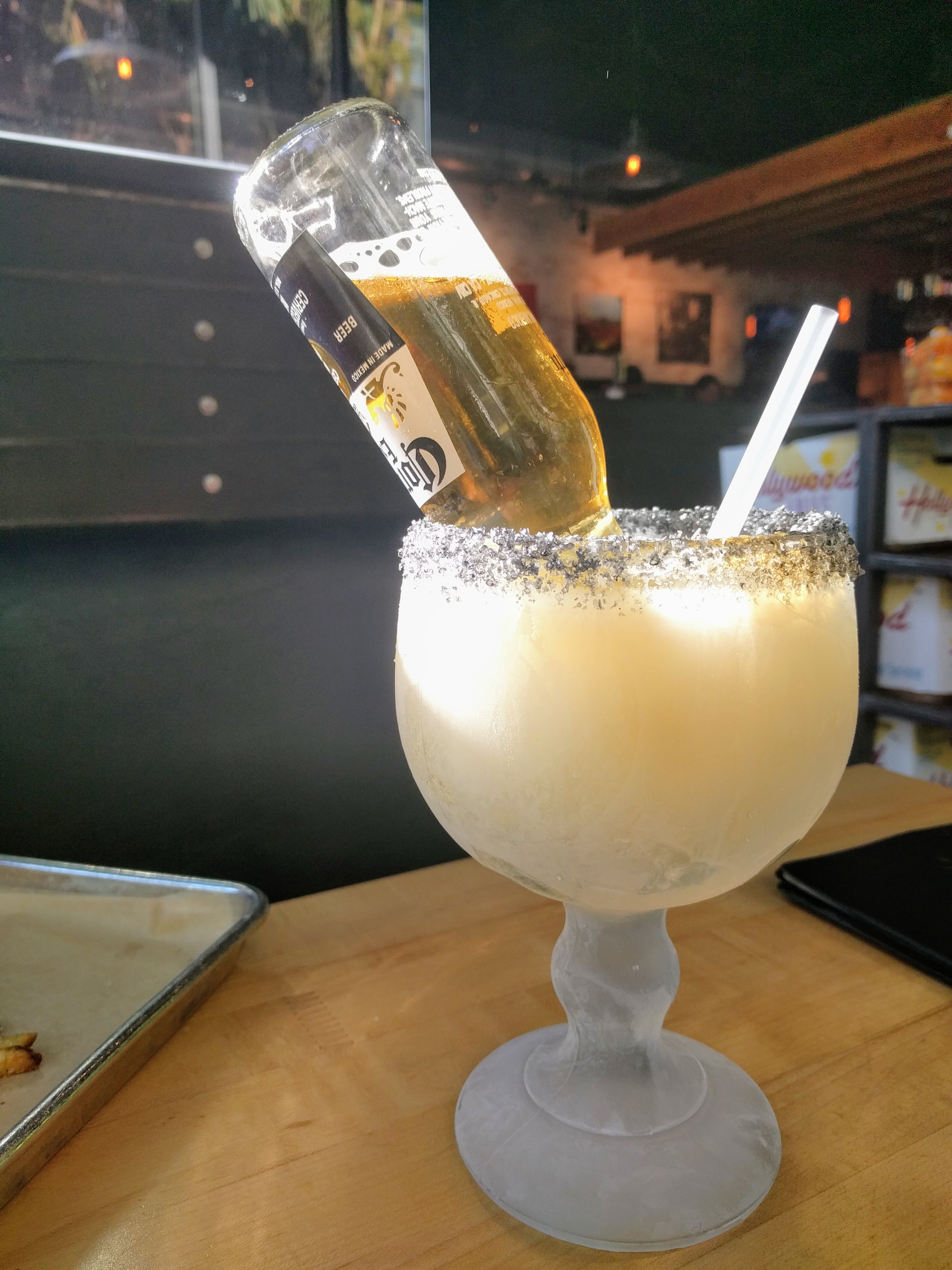 A Corona beer bottle turned upside down into a frosty goblet of margarita
