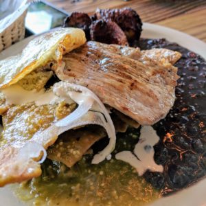 flattened steak on top of chilaquiles and beans