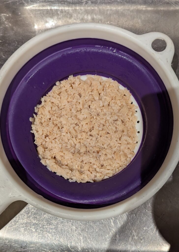 A strainer in a sink with cooked TVP.