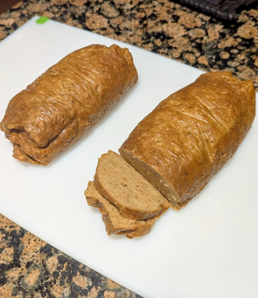 Two brown loaves of fake meat on a white cutting board.